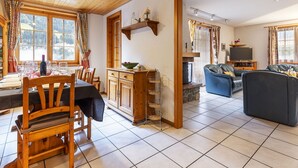 Ein gemütliches Wohnzimmer mit Kamin, einem Essbereich mit Tisch für vier Personen und einer Couch.