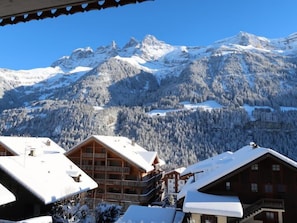 Un chalet de montagne doté de plusieurs balcons et offrant une vue sur les sommets enneigés.