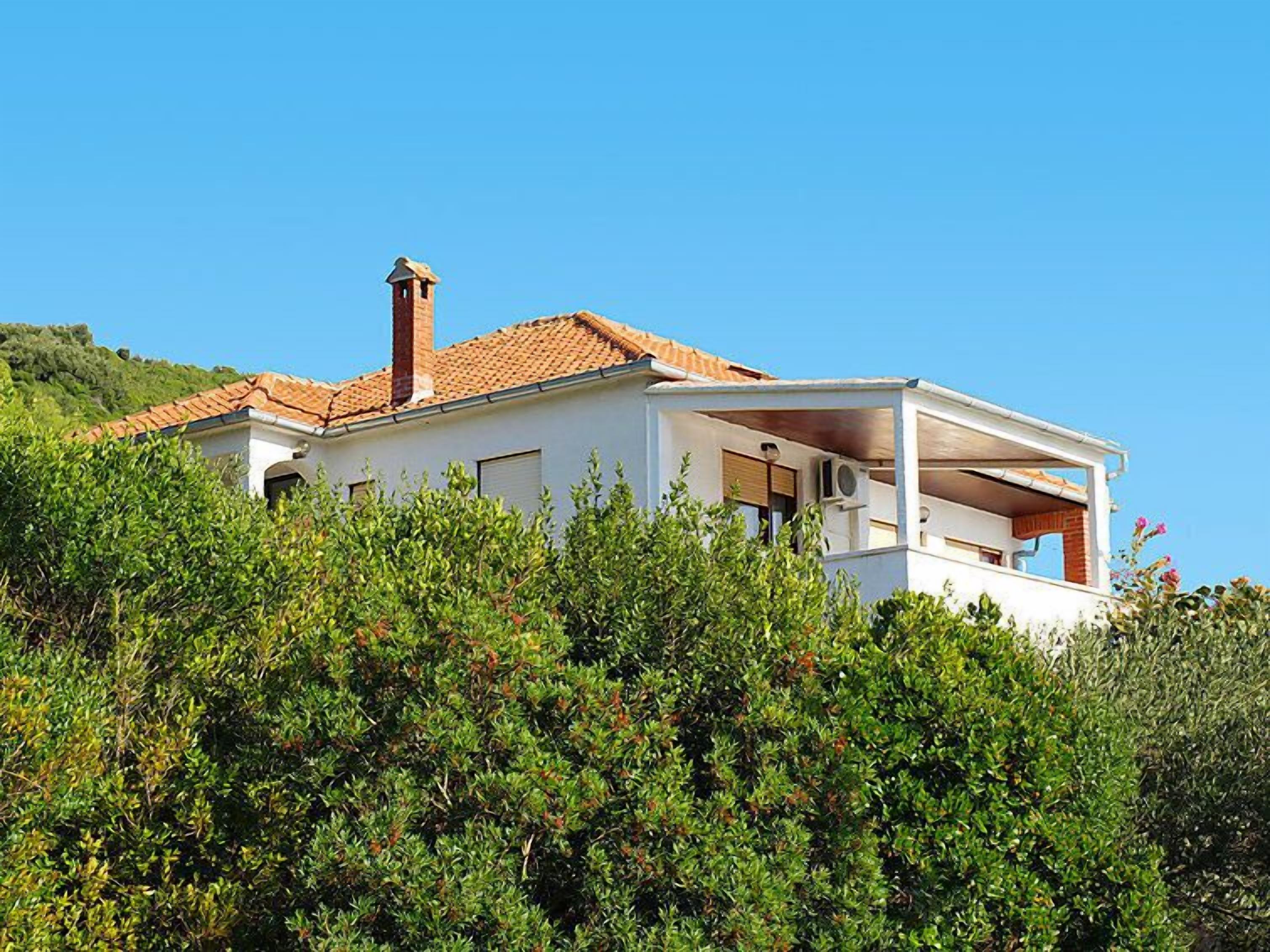 A modern house with a tiled roof, a chimney, and a balcony.