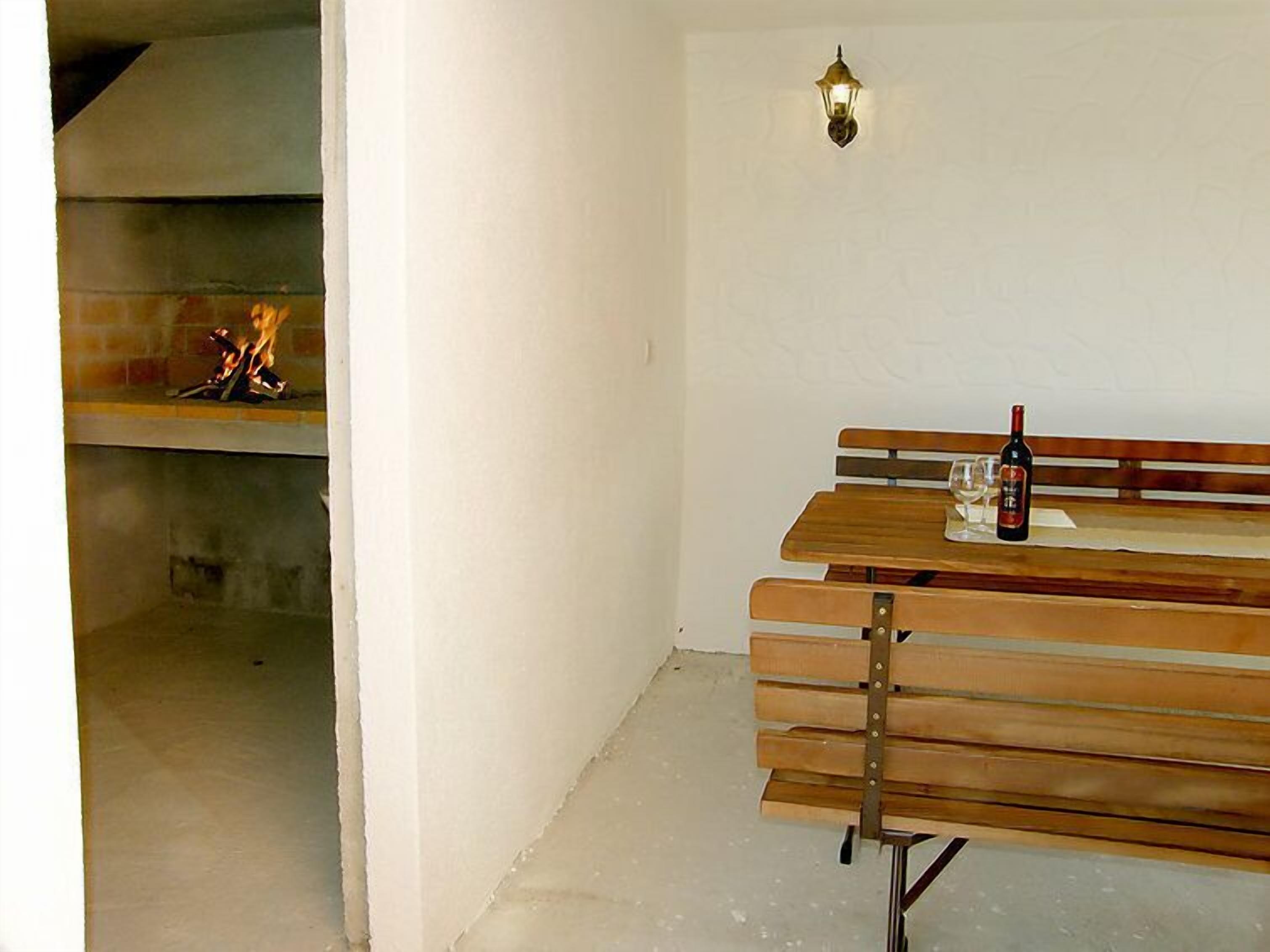Een kamer met een open haard, een houten bankje en een fles wijn op het bankje.