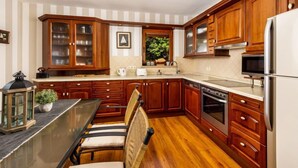 Une cuisine avec des meubles de rangement en bois, un réfrigérateur, une cuisinière et une table à manger avec des chaises.