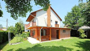A two-story house with a balcony, a covered porch, and a well-maintained lawn.