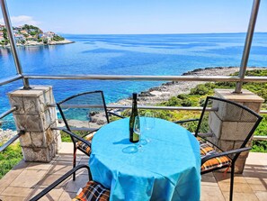 Enjoy a scenic coastal view from this outdoor seating area with a round table and two comfortable chairs.