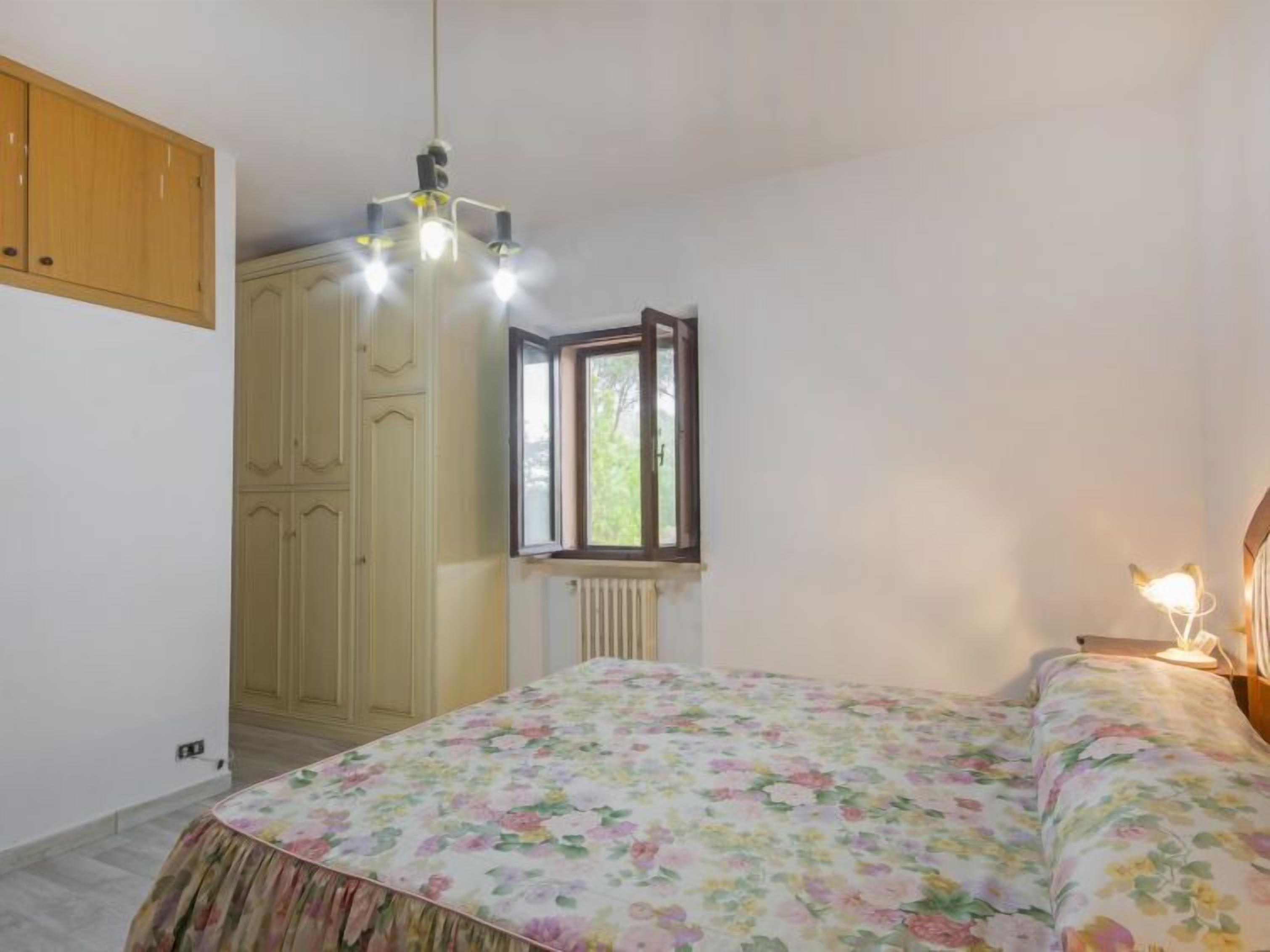 Een slaapkamer met een bed, een kledingkast, een raam en een radiator.