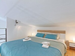 Ein modernes Schlafzimmer mit einem großen Bett, zwei Nachttischlampen und einem hölzernen Kopfteil.