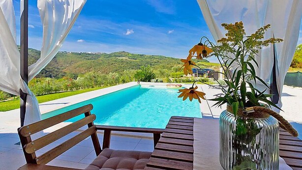 A pool with a clear view of the surrounding landscape, a bench, and a vase with flowers. - Vacation home Ravan by Interhome (Motovun)