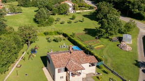 Una casa de dos pisos con techo de tejas, rodeada por un césped y jardín bien cuidados.