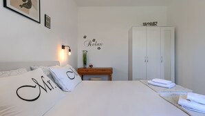 Ett sovrum med en säng, ett sängbord, en lampa, en garderob och dekorationer på väggen.