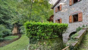 A stone building with wooden shutters, surrounded by lush greenery and a stone wall. - La Ripresa by Interhome (Vicchio)