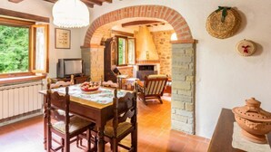 A rustic dining area with a wooden table and chairs, a fireplace, and a stone archway. - La Ripresa by Interhome (Vicchio)