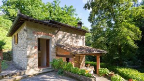 A stone cottage with a tiled roof, a wooden door, and a small porch with a table and chairs. - La Ripresa by Interhome (Vicchio)