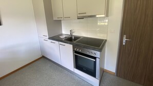 A compact kitchen with white cabinets, a stainless steel sink, and a built-in oven. - Apartments Carmena by Interhome (Saas-Grund)