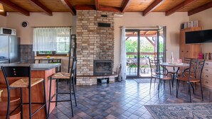 Una cocina acogedora con chimenea de ladrillo, vigas de madera y un comedor con sillas y mesa.