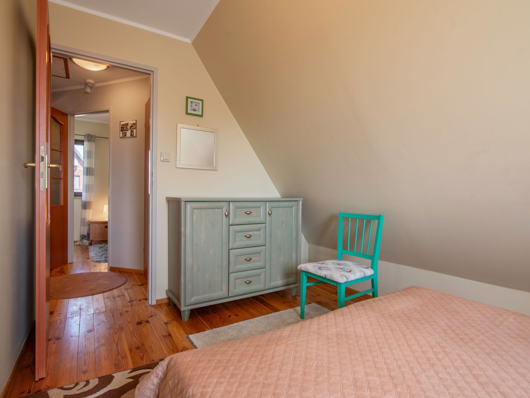 Un dormitorio con cama, cómoda, silla y puerta que da a otra habitación.