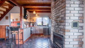 Una cocina con chimenea de piedra, vigas de madera y suelo de baldosas.