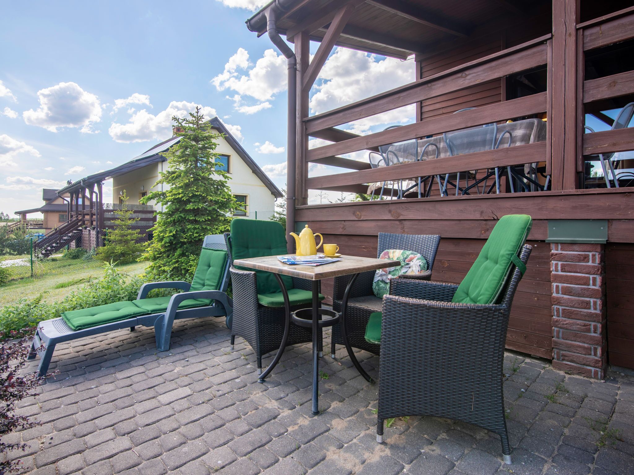 An outdoor patio with wicker furniture, a table, and a view of a building in the background.
