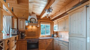 Eine holzhausartige Küche mit eingebautem Backofen, einem Fenster und Holzschränken.