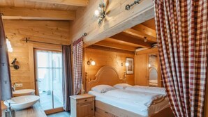 Ein Schlafzimmer einer Holzhütte mit einem Einzelbett, einem Nachttisch, einem eingebauten Waschbecken und einem Fenster mit Vorhängen.