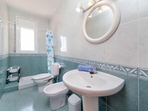 Une salle de bain équipée de toilettes, d’un bidet, d’un lavabo et d’un rideau de douche.