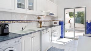 Une cuisine moderne avec des meubles blancs, un four à micro-ondes encastré et un lave-linge.