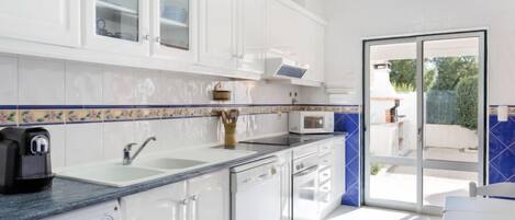 A modern kitchen with white cabinets, a built-in microwave, and a washing machine.