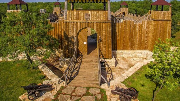 Une structure en bois dotée d’une arche centrale, entourée de sentiers pavés et de deux canons.