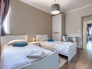 Une chambre moderne avec deux lits, un bureau et un luminaire suspendu.