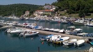 Un port de plaisance où sont amarrés différents types de bateaux, entouré de bâtiments et de verdure.