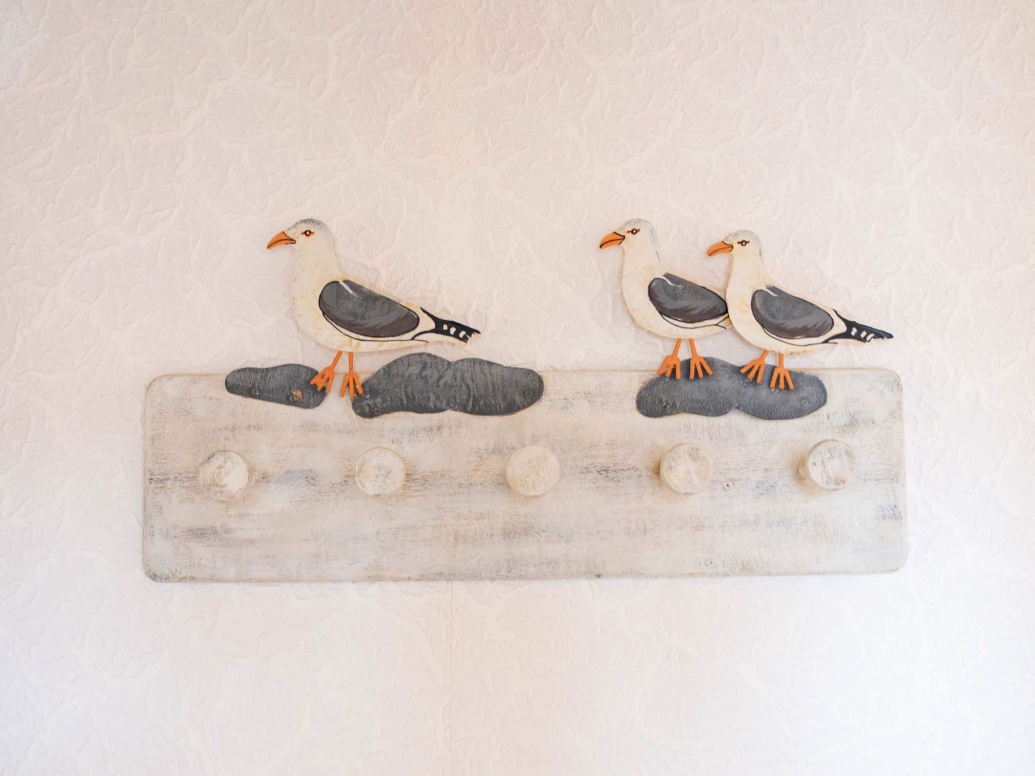 Une décoration rustique représentant des oiseaux, à fixer au mur, avec deux oiseaux perchés sur une planche de bois.