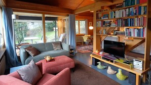 Una sala de estar acogedora con un sofá, un televisor y una estantería llena de libros.