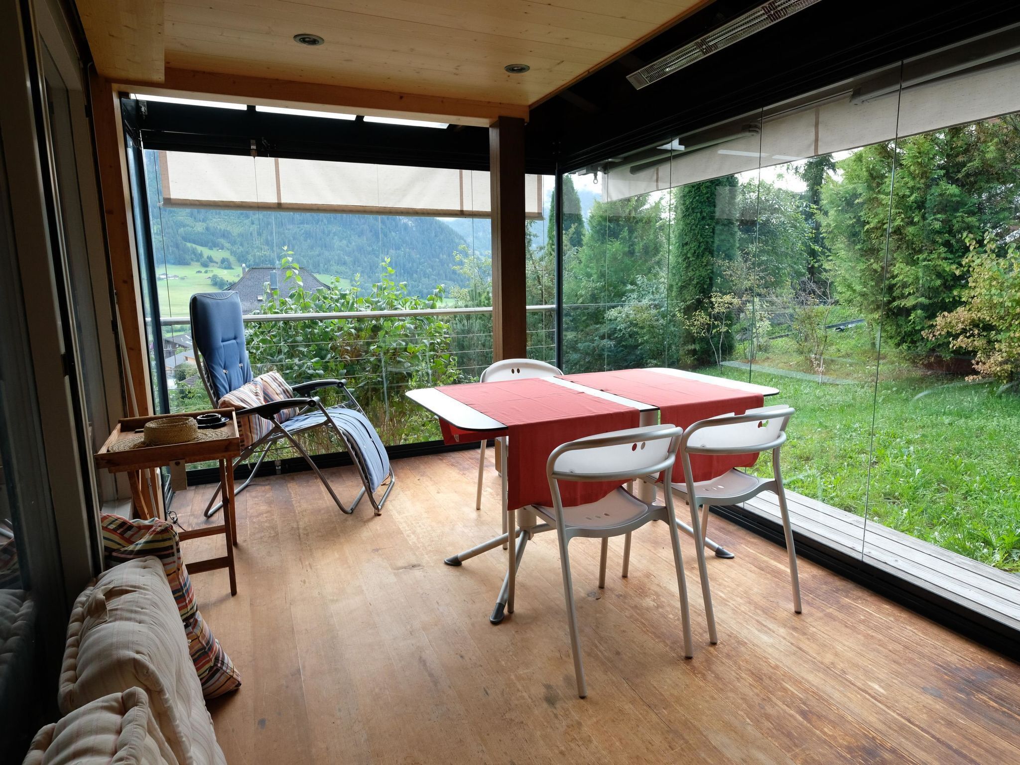 A balcony with a table and chairs, a sofa, and a view of a green landscape.