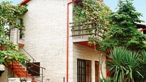 Um edifício de pedra com telhado vermelho, escadaria e varanda.