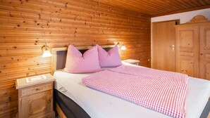 Een kamer met houten lambrisering, een bed, twee nachtkastjes en een garderobe.