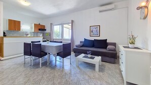 Een moderne woonruimte met een eethoek, bank en kitchenette.