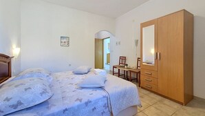 Een slaapkamer met een bed, een houten garderobe, een bureau en een stoel.