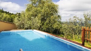Una piscina con acqua cristallina, circondata da vegetazione rigogliosa e alberi.