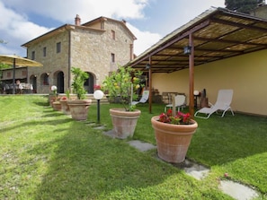 A stone building with a covered patio area, outdoor seating, and potted plants.