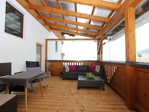 Un espace extérieur aménagé, abrité et doté d’un sol en bois, d’une table, d’un canapé et d’une petite table basse.