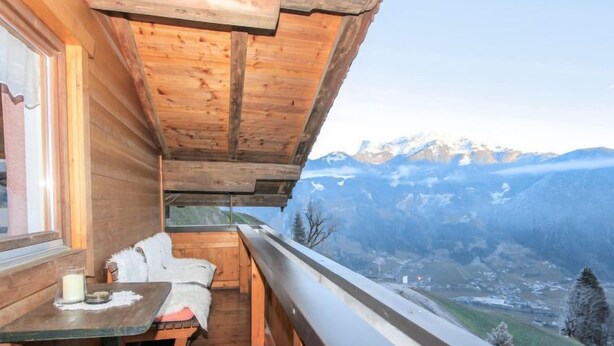 Una cabaña de madera con un balcón que da a un paisaje montañoso.