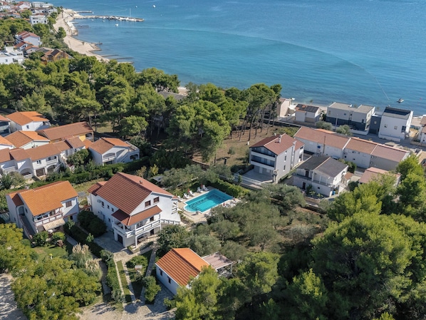 A coastal residential area with houses, a swimming pool, and a beach.