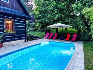 Ein Schwimmbecken mit einer Holzhütte und Liegestühlen.