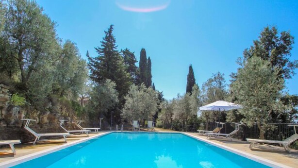A rectangular swimming pool with clear blue water, surrounded by stone tiles.