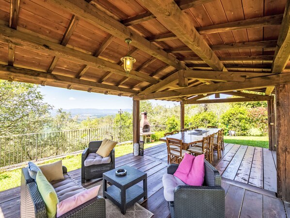 A covered outdoor deck with wicker furniture, a table, and a grill.