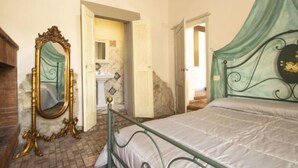 A bedroom with a metal bed frame, a large ornate mirror, and a green canopy bed.