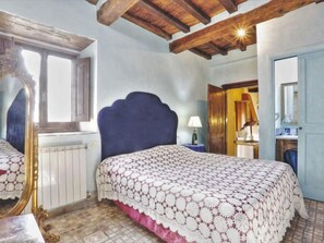 Un dormitorio con una cama grande, un espejo, una ventana y techo de madera.