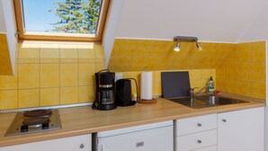Een keuken met een dakraam, gele tegels, een koffiezetapparaat, een keukenrolhouder, een zeepdispenser en een spoelbak.