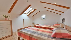 A bedroom with two beds, wooden beams, a dresser, and a small window. - Apartment Karlo by Interhome (Opatija/Rukavac)