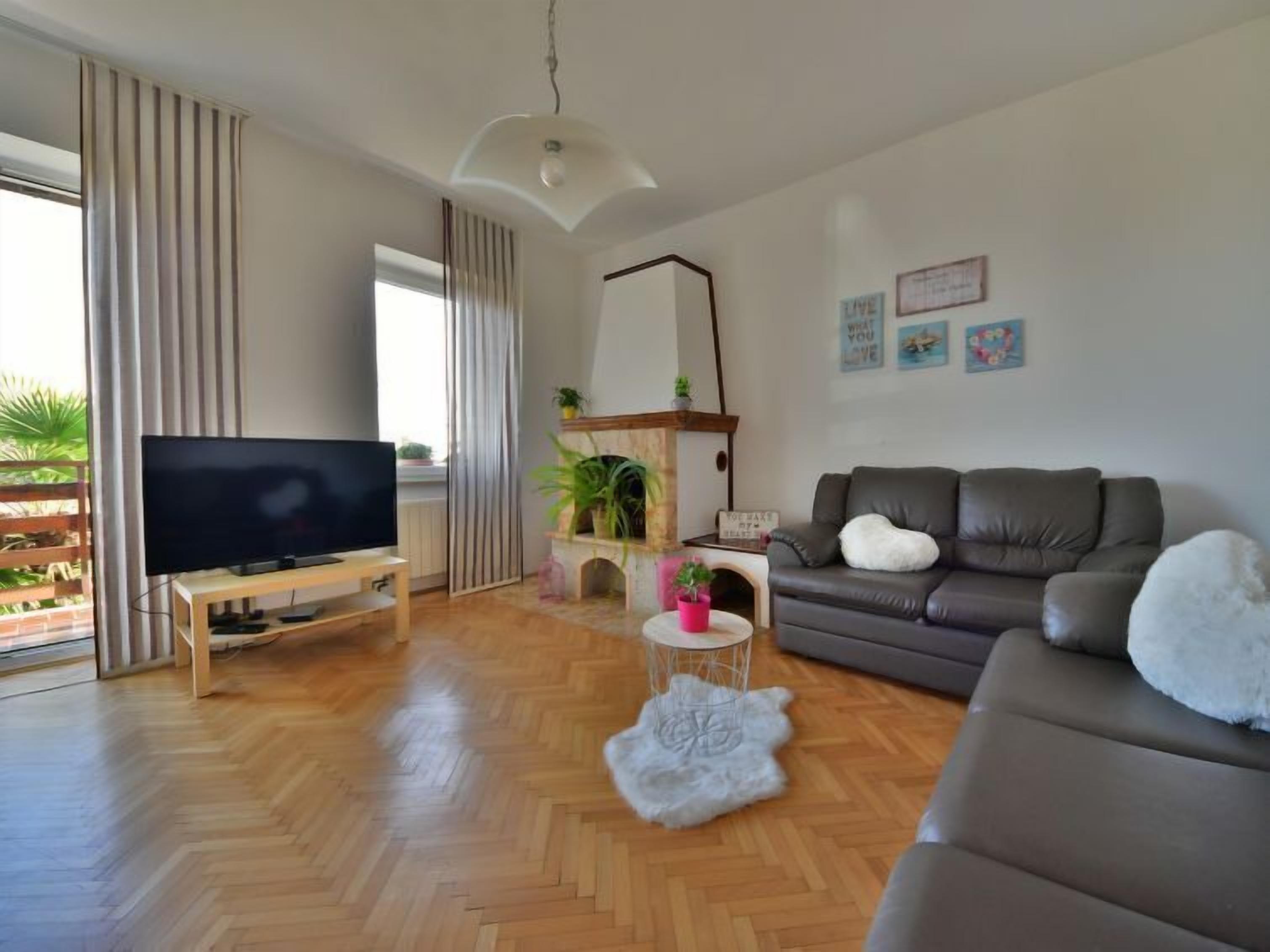 Un salon moderne avec un téléviseur à écran plat, un canapé en cuir, un tapis blanc et moelleux, et une cheminée.