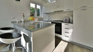 A modern kitchen with white cabinets, a central island, and pendant lighting. - Apartment Karlo by Interhome (Opatija/Rukavac)