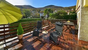 A terrace with a wooden deck, outdoor furniture, and a yellow umbrella. - Apartment Karlo by Interhome (Opatija/Rukavac)